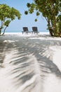 Two empty wooden deckchairs on idyllic sand beach