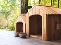 two empty wooden dog\'s houses with dog food bowls in balcony decorated with houseplant in plant pots