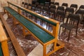 Two empty wooden pews in a church with chairs