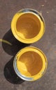 Two empty yellow paint cans with smudges stand on a rusty iron sheet lit by sunlight Royalty Free Stock Photo