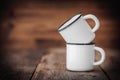 Two enameled cups on wooden rustic kitchen table. Royalty Free Stock Photo