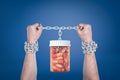 Two enchained male hands holding up a pills jar which is hanging on the same chain.