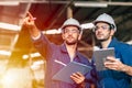 Two engineer worker working together with safety uniform and white helmet to work in industry factory handle tablet Royalty Free Stock Photo