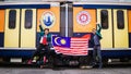 Two engineering students jumping and holding high the Malaysia flag with the UniKL and MARA logo