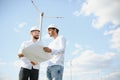 Two engineers discussing against turbines on wind turbine farm. Royalty Free Stock Photo