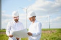 Two engineers discussing against turbines on wind turbine farm. Royalty Free Stock Photo