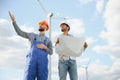 Two engineers discussing against turbines on wind turbine farm. Royalty Free Stock Photo