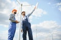 Two engineers discussing against turbines on wind turbine farm. Royalty Free Stock Photo