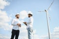 Two engineers discussing against turbines on wind turbine farm. Royalty Free Stock Photo