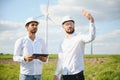 Two engineers discussing against turbines on wind turbine farm. Royalty Free Stock Photo