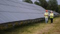 Two engineers are discussing drawings for the project. They are standing at a solar panel station. The female engineer Royalty Free Stock Photo