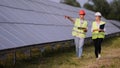 Two engineers are discussing drawings for the project. They are standing at a solar panel station. The female engineer Royalty Free Stock Photo