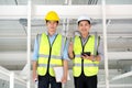 Two engineers man standing in the site. Engineer holding tablet and smile and thumbs up and other engineer holding chart