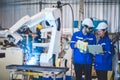 Two engineers mechanic using computer controller Robotic arm for welding steel in steel factory workshop. Industry robot