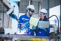 Two engineers mechanic using computer controller Robotic arm for welding steel in steel factory workshop. Industry robot