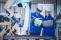 Two engineers mechanic using computer controller Robotic arm for welding steel in steel factory workshop. Industry robot