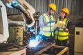 Two engineers mechanic using computer controller Robotic arm for welding steel in steel factory workshop. Industry robot
