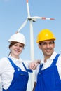 Two engineers posing with wind turbine and solar panels