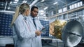 Two Engineers Talk, Use Tablet Computer while Working on Satellite Construction. Aerospace Agency Royalty Free Stock Photo