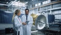 Two Engineers Talk, Use Tablet Computer while Working on Satellite Construction. Aerospace Agency Royalty Free Stock Photo