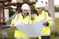 Two engineers are talking in front of electrical transmission lines, working on renewable energy development. Engineers Royalty Free Stock Photo