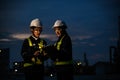 Two engineers, wearing helmets and reflective vests, work on a laptop at night at an industrial site. Industrial plant and Royalty Free Stock Photo
