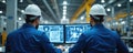 Two engineers work at factory. Men in helmets work with computer monitors with engineering diagrams. Workers control industrial Royalty Free Stock Photo