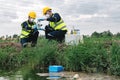 Two Environmental Engineers Inspect Water Quality and Take Water Samples Notes in The Field Near Farmland, Natural Water Sources Royalty Free Stock Photo