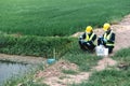 Two Environmental Engineers Inspect Water Quality and Take Water Samples Notes in The Field Near Farmland, Natural Water Sources Royalty Free Stock Photo