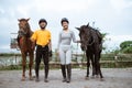 Two equestrian athletes wearing gear standing next to their horses