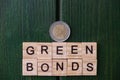 A two euro coin, above an inscription, green bonds, above a green, door. Investment concept for ecology by the European Union