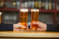 Two men cling to full glasses with a beer. Close-up. Royalty Free Stock Photo