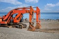 Two excavators with lowered buckets stand on the seashore Royalty Free Stock Photo