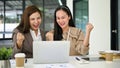 Two excited Asian businesswomen showing clenched fists, rejoicing and celebrating