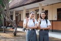 Two excited high school teens smiling with okay hand gesture