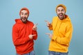 Two excited hipster men guys in fashion red yellow clothes posing isolated on pastel blue background studio portrait