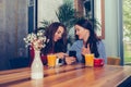 Two excited young girls using mobile phone while sitting in cafe Royalty Free Stock Photo