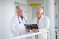 Two experienced male doctors discussing x-rays in hospital corridorb