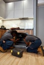 Two repairpersons fixing kitchen oven, back view Royalty Free Stock Photo