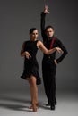 Expressive dancers in black clothing performing tango on grey background
