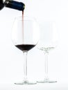 Two exquisite transparent glasses with red wine and a bottle pouring wine on a white background Royalty Free Stock Photo