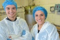 Two factory workers posing in front vats