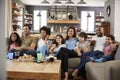 Two Families Sitting On Sofa Watching Television Together Royalty Free Stock Photo