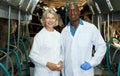 Two farm milkmaids male and female standing near modern cow milking machines Royalty Free Stock Photo