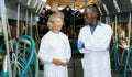 Two farm milkmaids male and female standing near modern cow milking machines Royalty Free Stock Photo