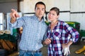 Two farm workers colleagues working in greenhouse. Experienced man showing what and where to woman