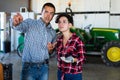 Two farm workers colleagues working in greenhouse. Experienced man showing what and where to woman