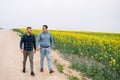 Two farmers in a field examining rape crop. Agribusiness concept. agricultural engineer standing in a rape field Royalty Free Stock Photo