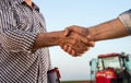 Two farmers shaking hands in field during harvest Royalty Free Stock Photo