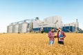 Two farmers stand in a wheat field with tablet. Agronomists discuss harvest and crops among ears of wheat with grain Royalty Free Stock Photo